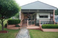 a house with a covered porch and steps leading up to the front door, next to a small tree