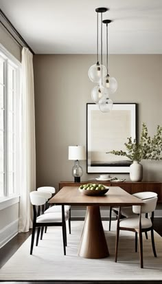 a dining room table with chairs and a bowl of fruit on the table in front of it