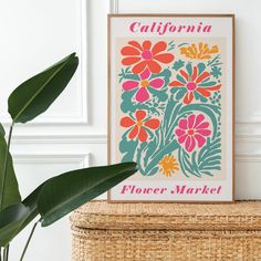 a flower market poster sitting on top of a wicker basket next to a plant