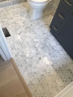 a white toilet sitting next to a wooden floor in a bathroom on top of a hard wood floor