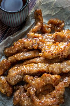 chicken wings are piled on top of each other next to a cup of hot sauce