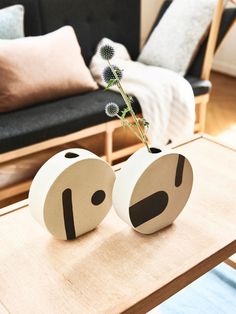 two vases with flowers in them sitting on a coffee table next to a couch