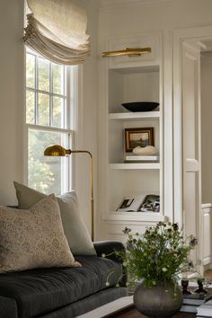 a living room filled with furniture and a book shelf in front of a large window