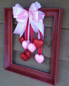 a frame with hearts hanging from it and a bow on the front door hanger