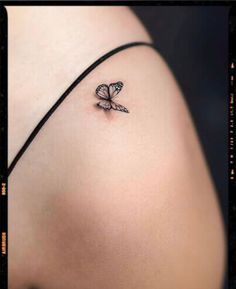 a small butterfly tattoo on the back of a woman's shoulder