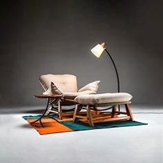 a chair with a lamp on top of it sitting in front of a couch and rug