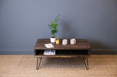 a coffee table with two mugs and a potted plant sitting on top of it