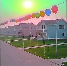 many balloons are floating in the air near houses