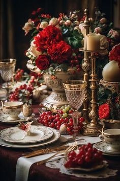 the table is set with red flowers and candles