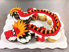 cupcakes decorated with red and yellow icing are on a white platter