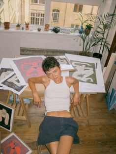 a woman laying on the floor in front of some pictures and art work with her hands behind her head