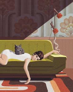 a woman laying on top of a green couch next to a cat