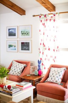 a living room with two orange chairs and a coffee table in front of the window