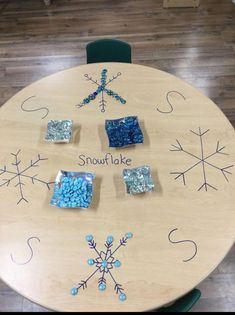 a wooden table topped with snowflakes and small square pieces of blue glass sitting on top of it