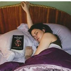 a woman laying in bed next to a book