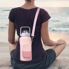 a woman sitting on the beach with her back turned to the camera bag and looking at the ocean