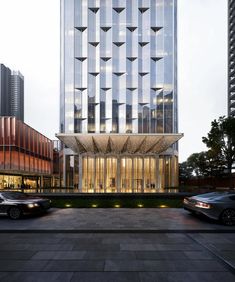 an office building in the middle of a city with cars parked on the street outside