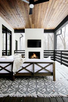 a large bed sitting under a wooden ceiling next to a fire place in a living room