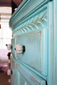 an old blue dresser with knobs on it's doors and drawers in a room