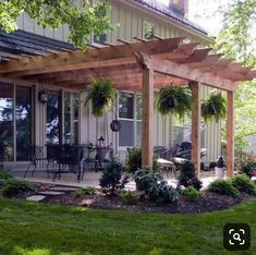 an outdoor patio with wooden pergols and plants on the ground in front of a house