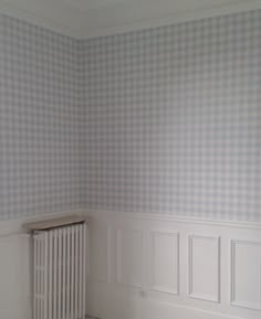 an empty room with a radiator and checkered wallpaper on the walls