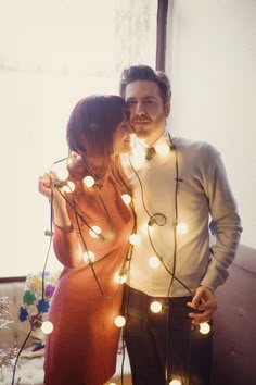 a man and woman standing next to each other with christmas lights on their foreheads