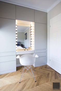 a white chair sitting in front of a mirror on top of a hard wood floor