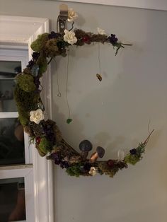 a wreath made out of moss and flowers hangs on the wall next to a door