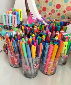 several cups filled with different colored pens and pencils