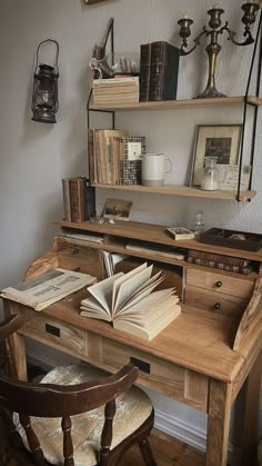 a wooden desk topped with lots of books next to a wall mounted shelf filled with pictures