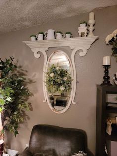 a living room filled with furniture and plants on top of a wall mounted above a mirror