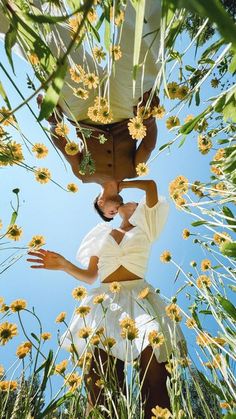 two men standing in the middle of a field with yellow flowers on their heads and arms