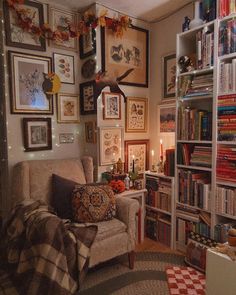 a living room filled with lots of books and pictures hanging on the wall next to a couch