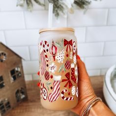 a hand holding a cup with christmas decorations on it and a straw in the cup