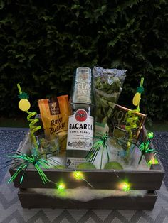 a box filled with drinks and snacks on top of a table next to some trees