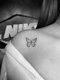 a black and white photo of a butterfly on the back of a woman's shoulder