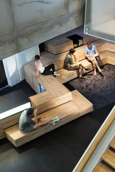 three people sitting on wooden benches in a building