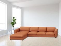 an orange sectional sofa sitting on top of a hard wood floor next to a potted plant