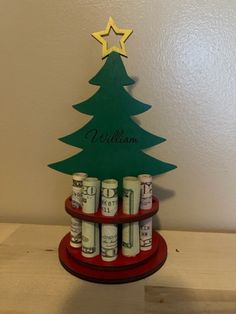 a christmas tree made out of stacks of money on top of a wooden stand with the name william written on it