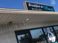 the sign for breakfast at tiffany's in front of a building with large windows