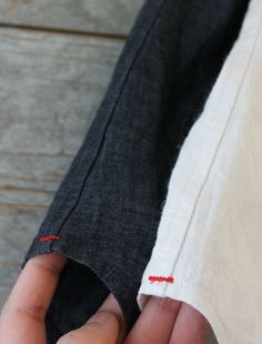 someone is sewing something on the side of a piece of cloth with red stitching