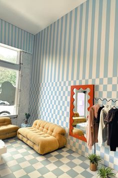 a living room with checkered wallpaper and furniture in it, including a futon sofa