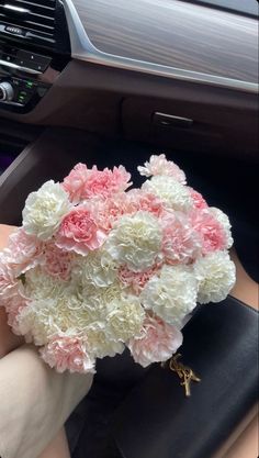 a bouquet of pink and white flowers sitting on top of a car dash board holder