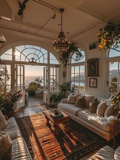 a living room filled with furniture and lots of windows overlooking the ocean in front of it