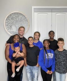 a group of people standing next to each other in front of a white door with a tree on it