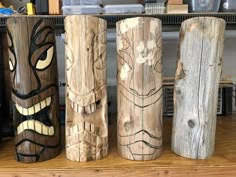 four wooden carved faces are lined up in a row on the shelf next to each other