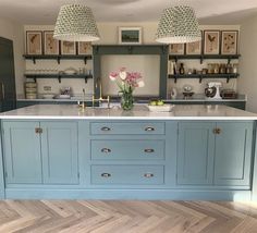 a large kitchen with blue cabinets and white counter tops, two hanging lights above the island