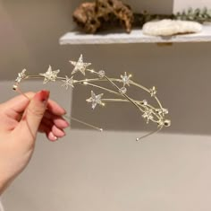 a hand holding a gold tiara with stars and crystals on the headpieces