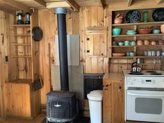 a stove top oven sitting inside of a kitchen next to wooden shelves and cupboards