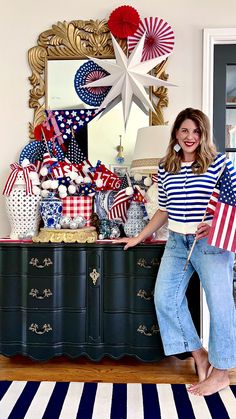 a woman standing in front of a dresser holding an american flag